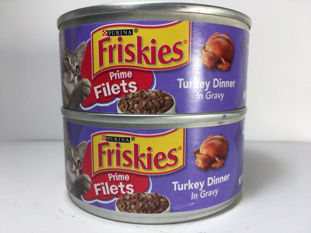 The front of two cans of delicious cat food stacked together, friskies, Prime Filets, Turkey Dinner in Gravy